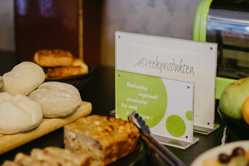 Assorted bread and pastries on a table with a acrylic sign in the background.