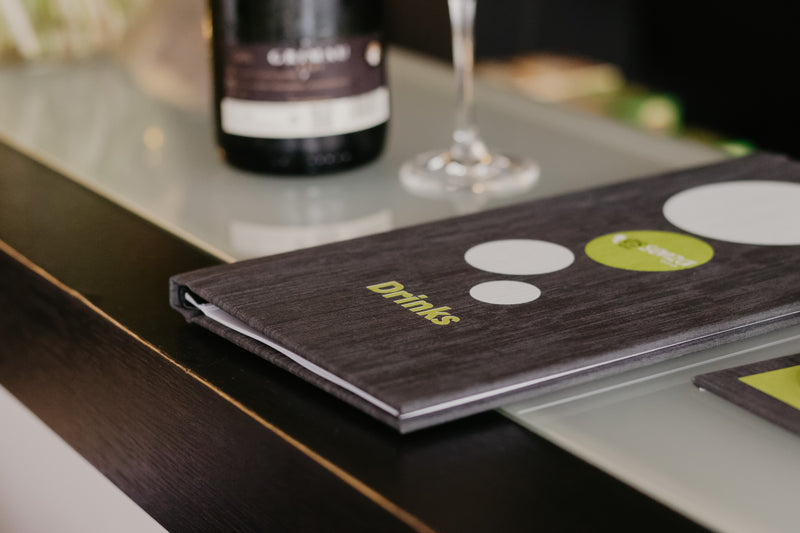 Menu on a table with a bottle and glass in the background