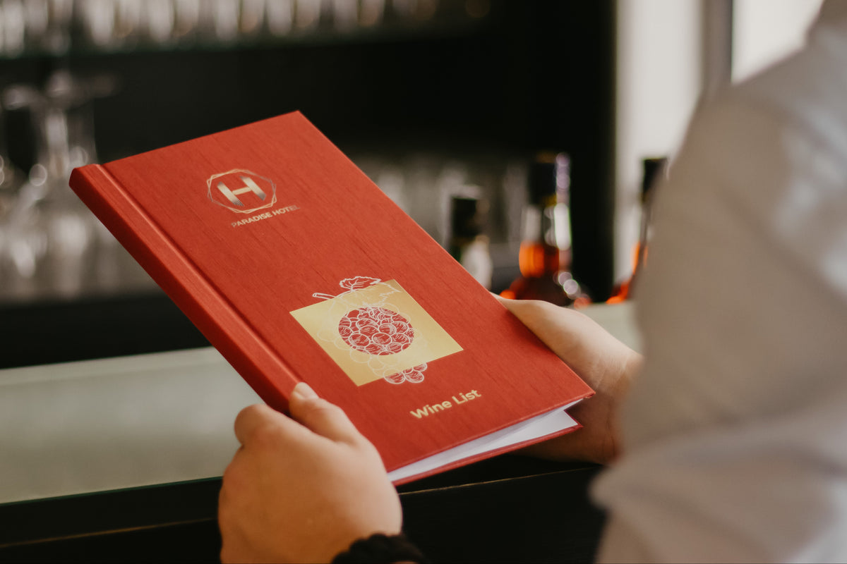 Rode menukaart met logo voor bar of restaurant in de hand van een gast