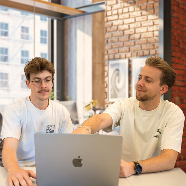 Two men working on a laptop in a modern office.