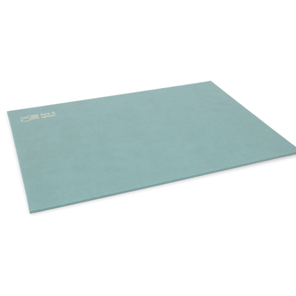 A blue rectangular placemat made from vegan leather, with a subtle textured surface and visible stitching along the edges.