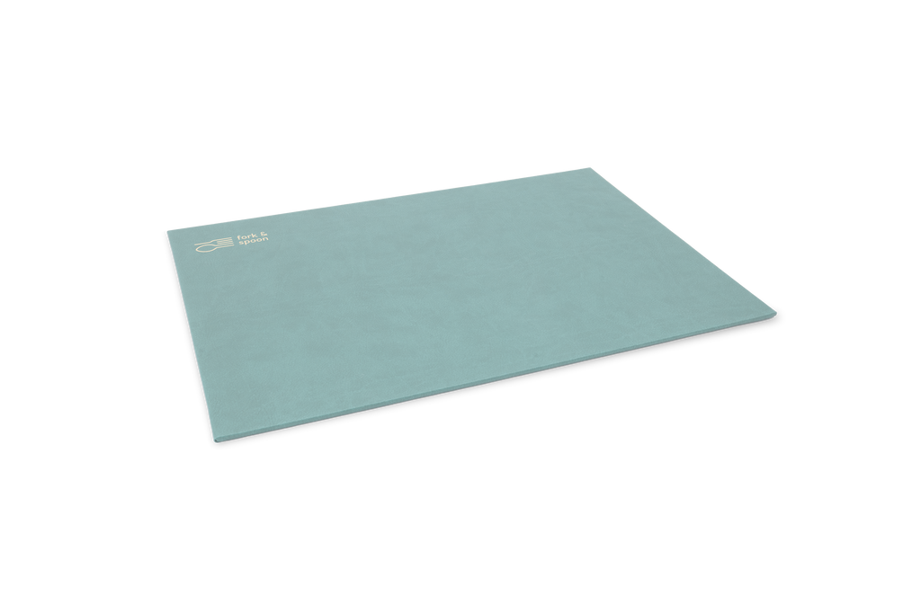 A blue rectangular placemat made from vegan leather, with a subtle textured surface and visible stitching along the edges.