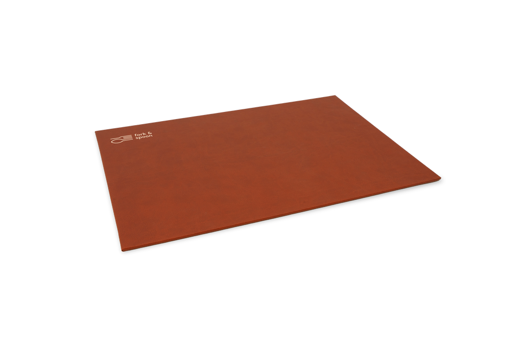 A brown rectangular placemat made from vegan leather, with a subtle textured surface and visible stitching along the edges.