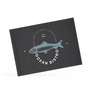 A classy clamp menu with a black cover featuring a white 'ocean bistro' logo.