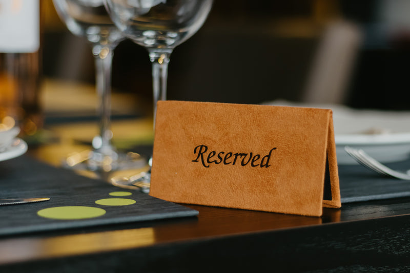 Reserved sign on a table with wine glasses and place mats in the background