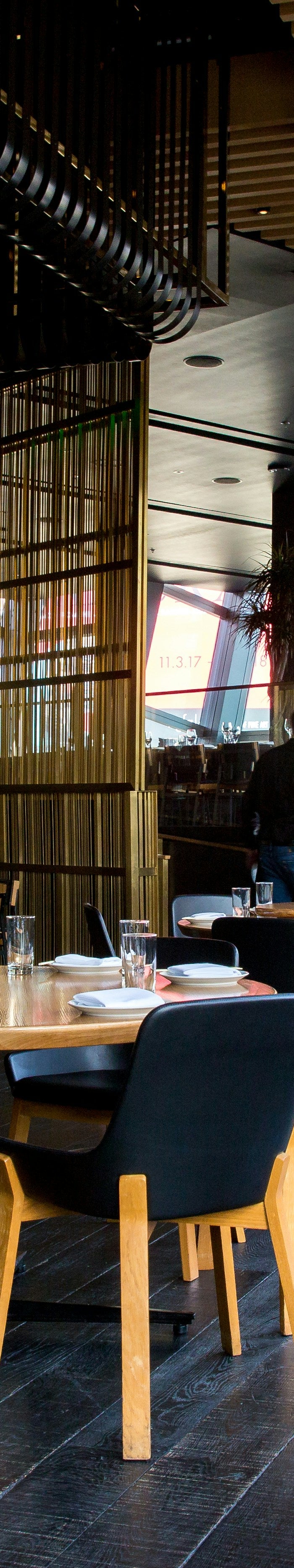 Modern restaurant interior with tables, chairs, and decorative elements.