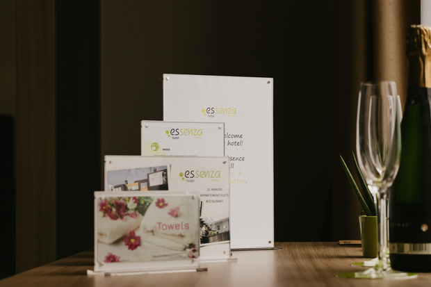 Collection of 'es service' branded acrylic panels on a table with a glass and bottle in the background.