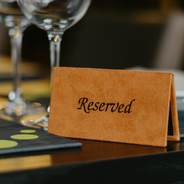 Reserved sign on a table with wine glasses and place mats in the background